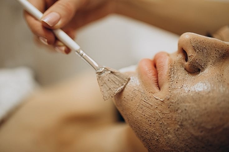 Applying facial mask treatment in a spa setting