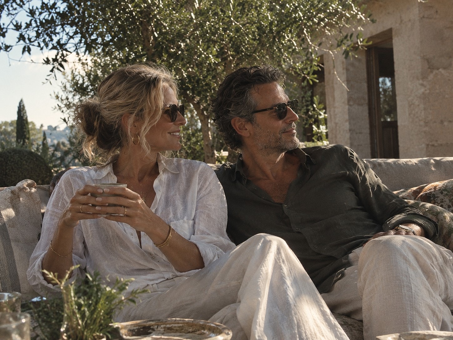 Couple enjoying coffee in a sunny outdoor setting.